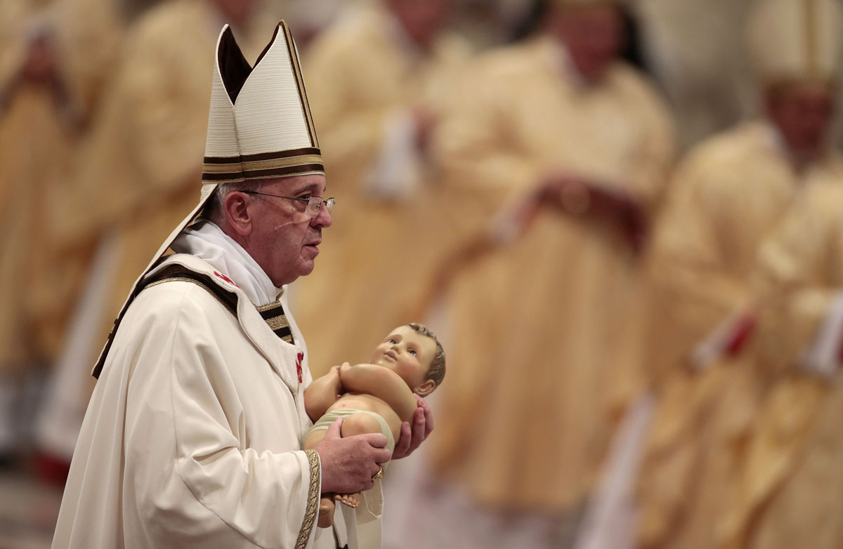 Pope Francis holds the baby Jesus statue at the end of the Christmas night mass in the Saint Peter's Basilica at the Vatican